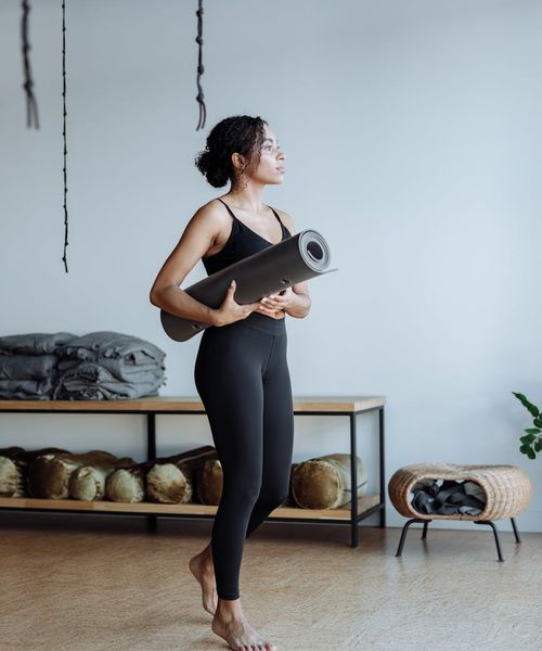 A focused individual practicing a balancing yoga pose in a dark, calm studio.
